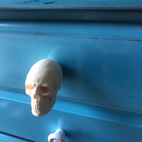 A bone-white resin skull knob fitted to a teal painted dresser drawer